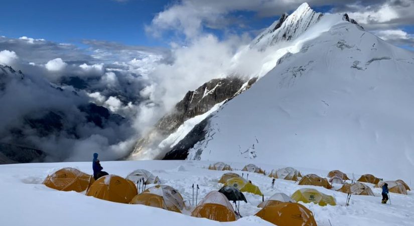Snow covered Manaslu peak towering above icy ridges under a clear sky during the Manaslu Expedition mountaineeing climb.