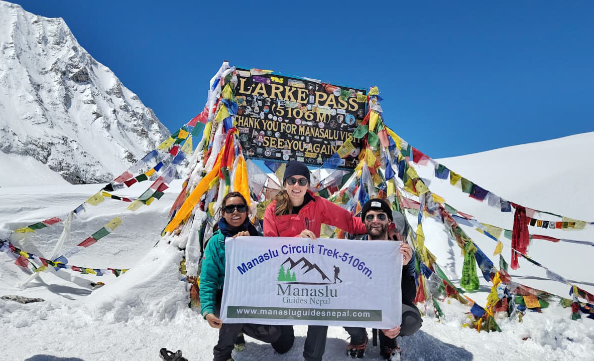 Trekkers at Larkya La Pass 5106m with prayer flags during 13 Days Manaslu Circuit Trek Nepal